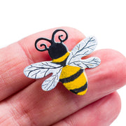Bee brooch on tips of the index and middle fingers